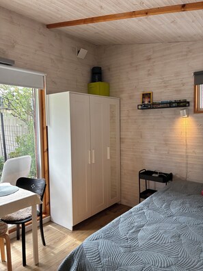 Ein Schlafzimmer mit einem Bett, einem Kleiderschrank, einem Schreibtisch mit Stuhl und einem Nachttisch.
