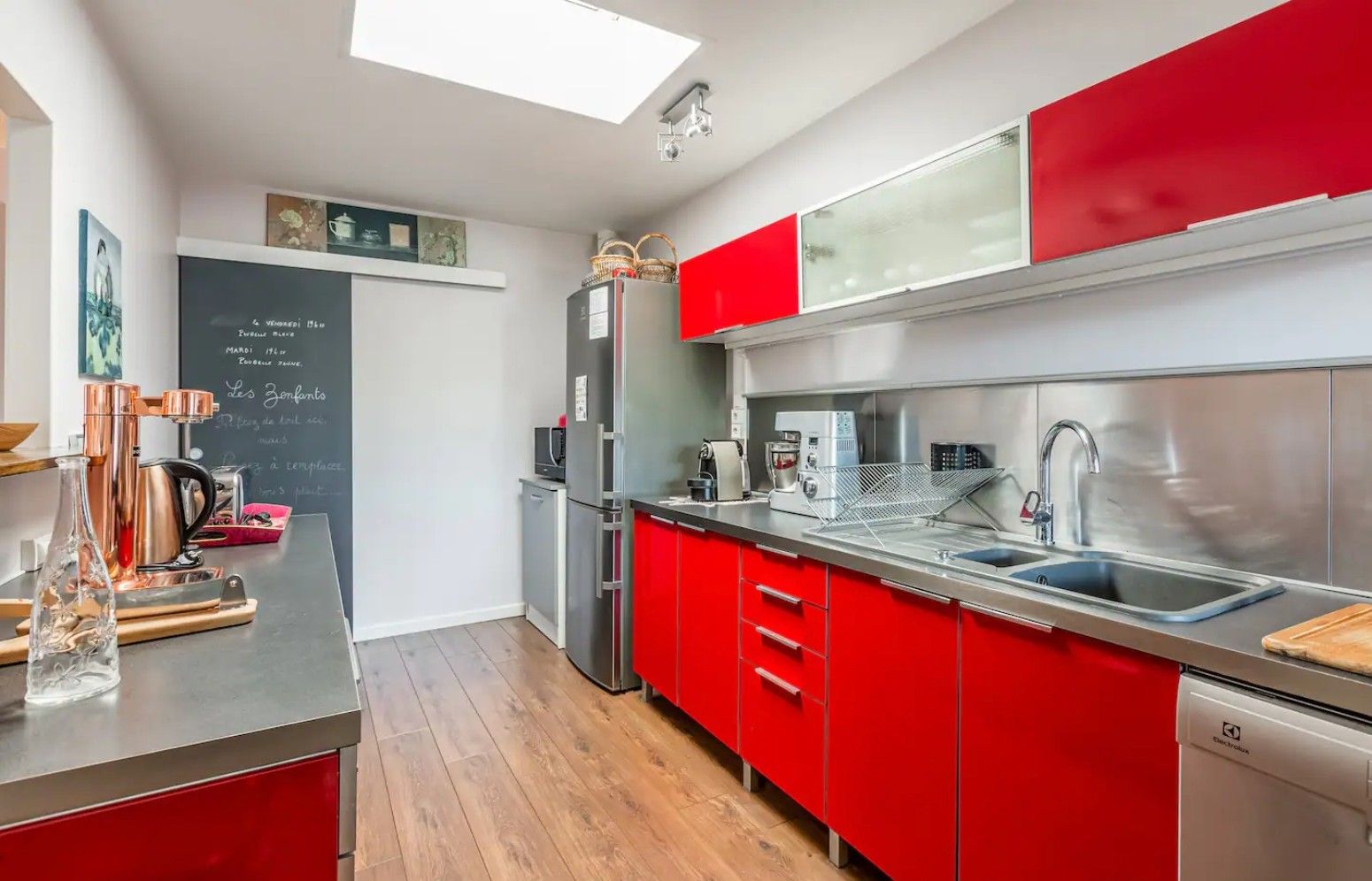 Una cocina moderna con armarios rojos, electrodomésticos de acero inoxidable y un tragaluz.