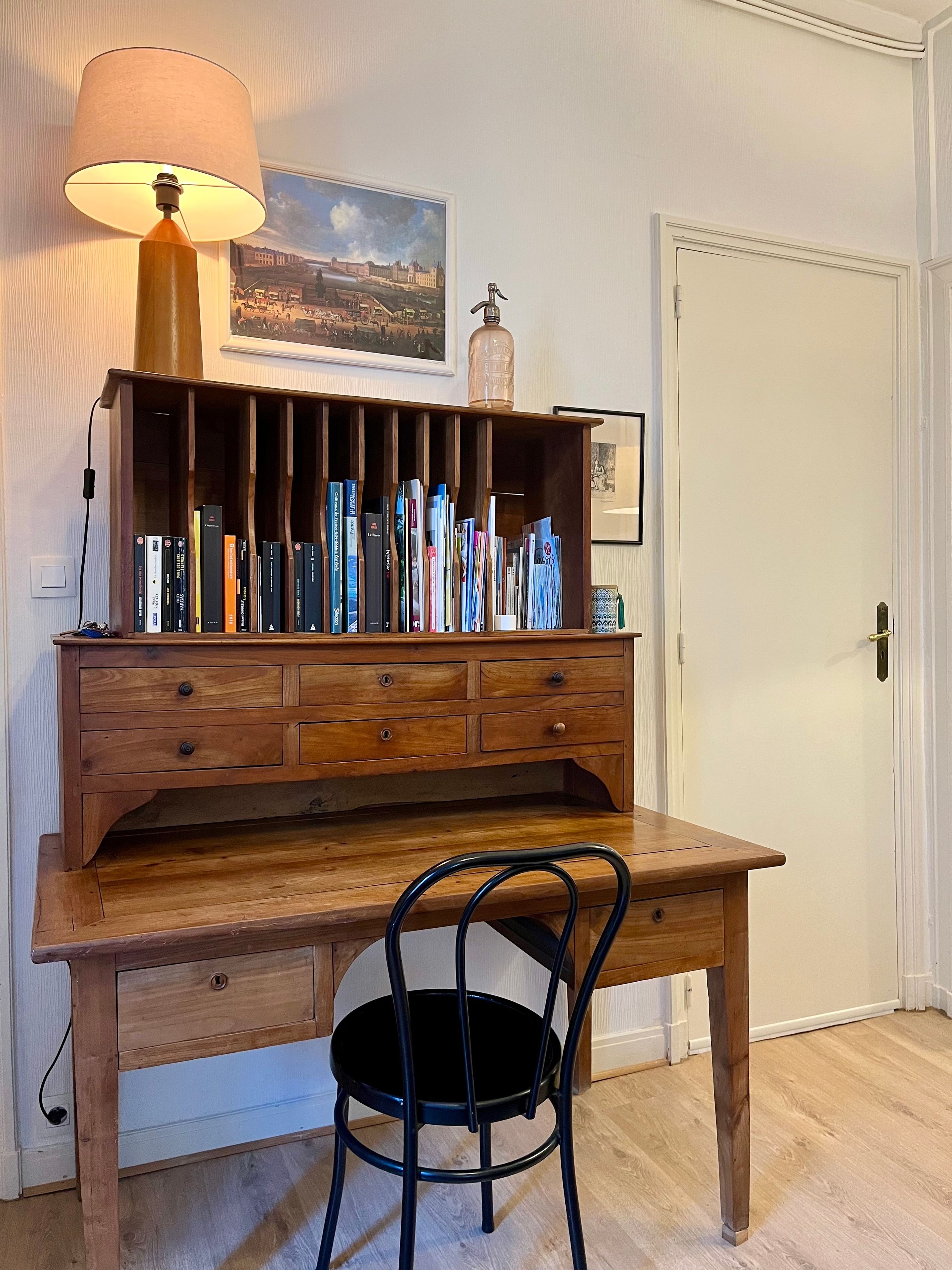 Ein Holztisch mit einer Lampe, einem Stuhl und einer Bücherwand voller Bücher.