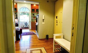 A hallway with a white bench, a door with a lock, and a small table with a vase. - CENTRAL ROME APARTMENT WITH TERRACE, ENSUITE BEDROOM AND MODERN COMFORTS (Roma)