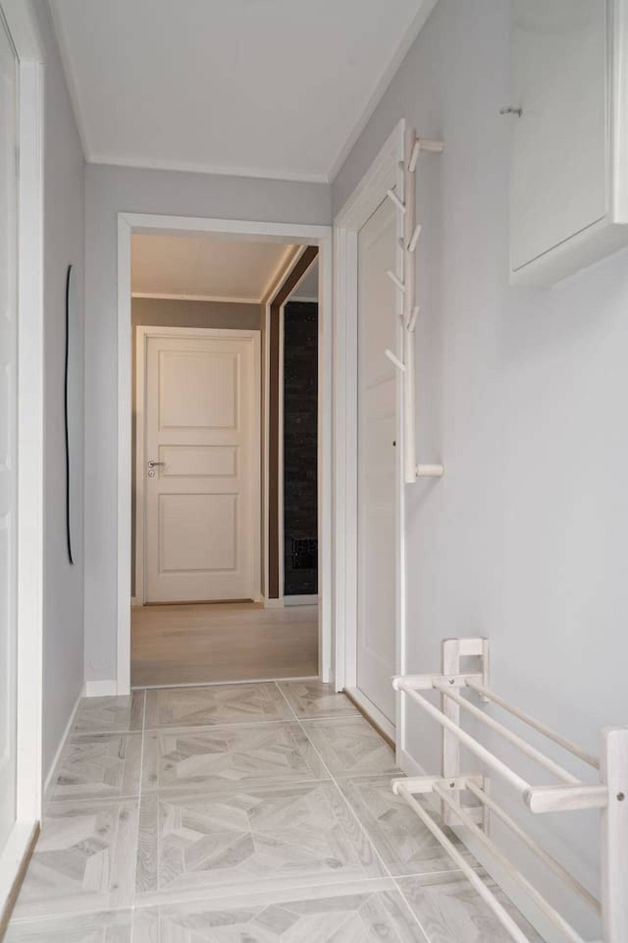 A hallway with a white door, a white radiator, and a tiled floor.