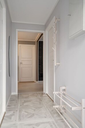 A hallway with a white door, a white radiator, and a tiled floor. - Winter Garden Apartment | Tromsø City (Tromsø)