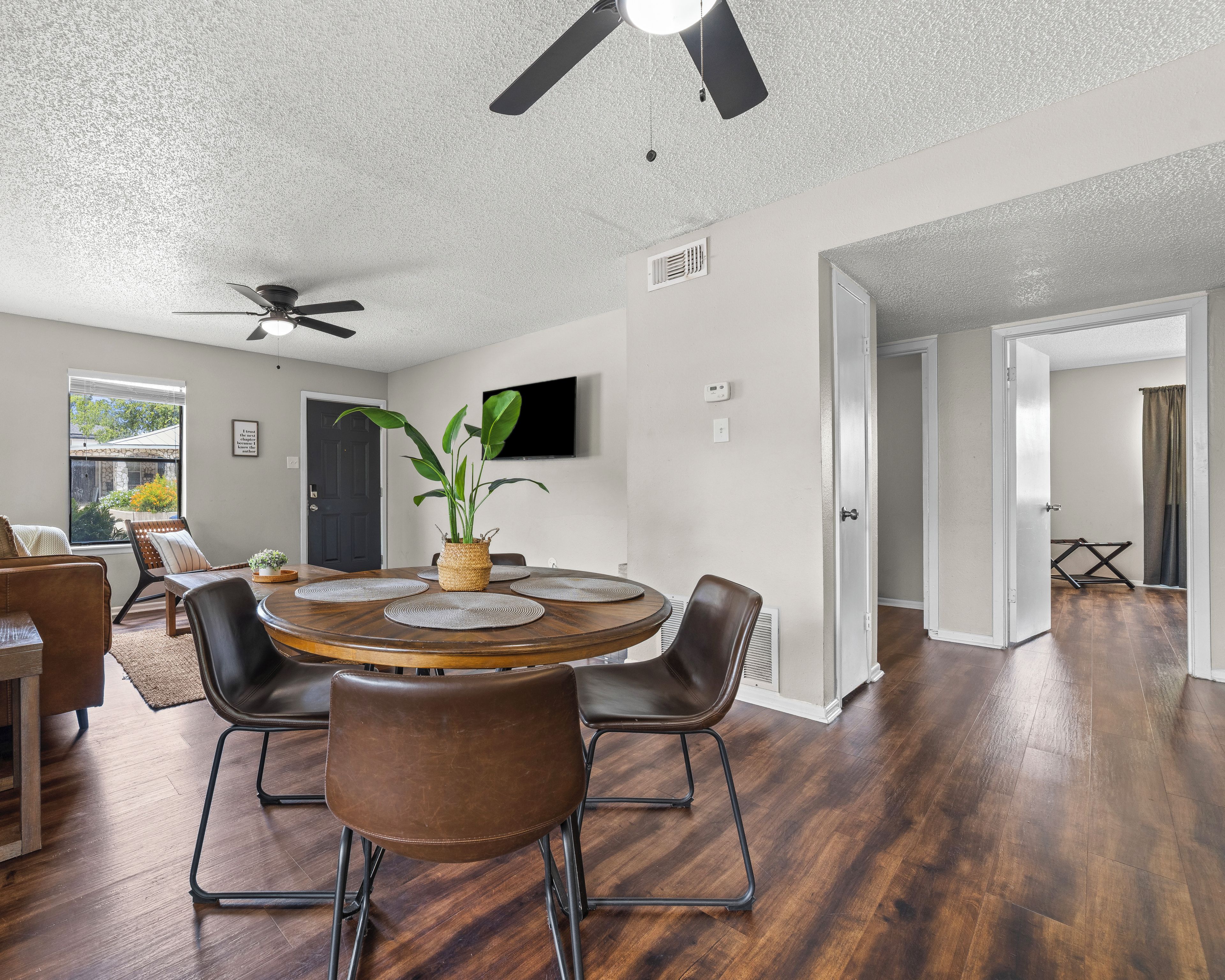 A dining area with a round table, chairs, and a ceiling fan.