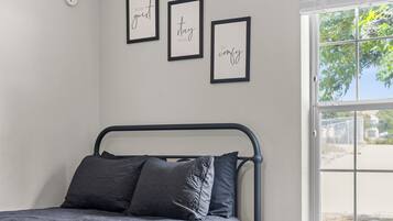 A bedroom with a bed, a window, and three framed inspirational quotes on the wall.