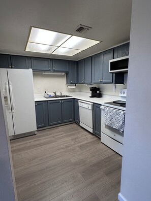 A modern kitchen with grey cabinets, a white refrigerator, a dishwasher, a stove, and a microwave. - Modern 2-bedroom condo close to Hospitals and Shops-centrally located Rio Rancho (Rio Rancho)