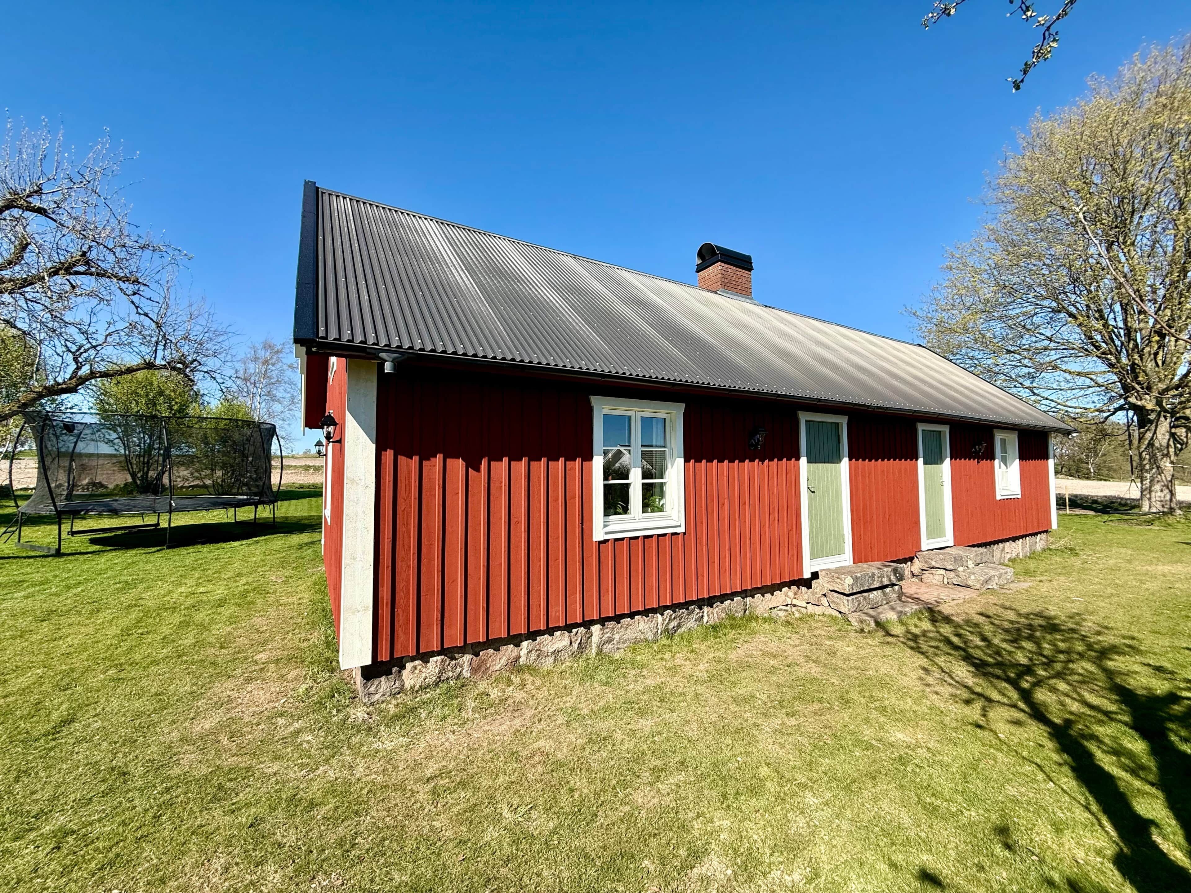 Une maison en bois rouge avec un toit en métal, une fenêtre et une porte.
