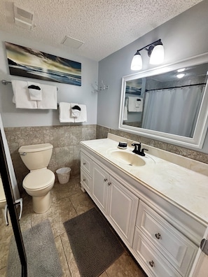 Een badkamer met toilet, wastafel, opbergmeubel en spiegel.