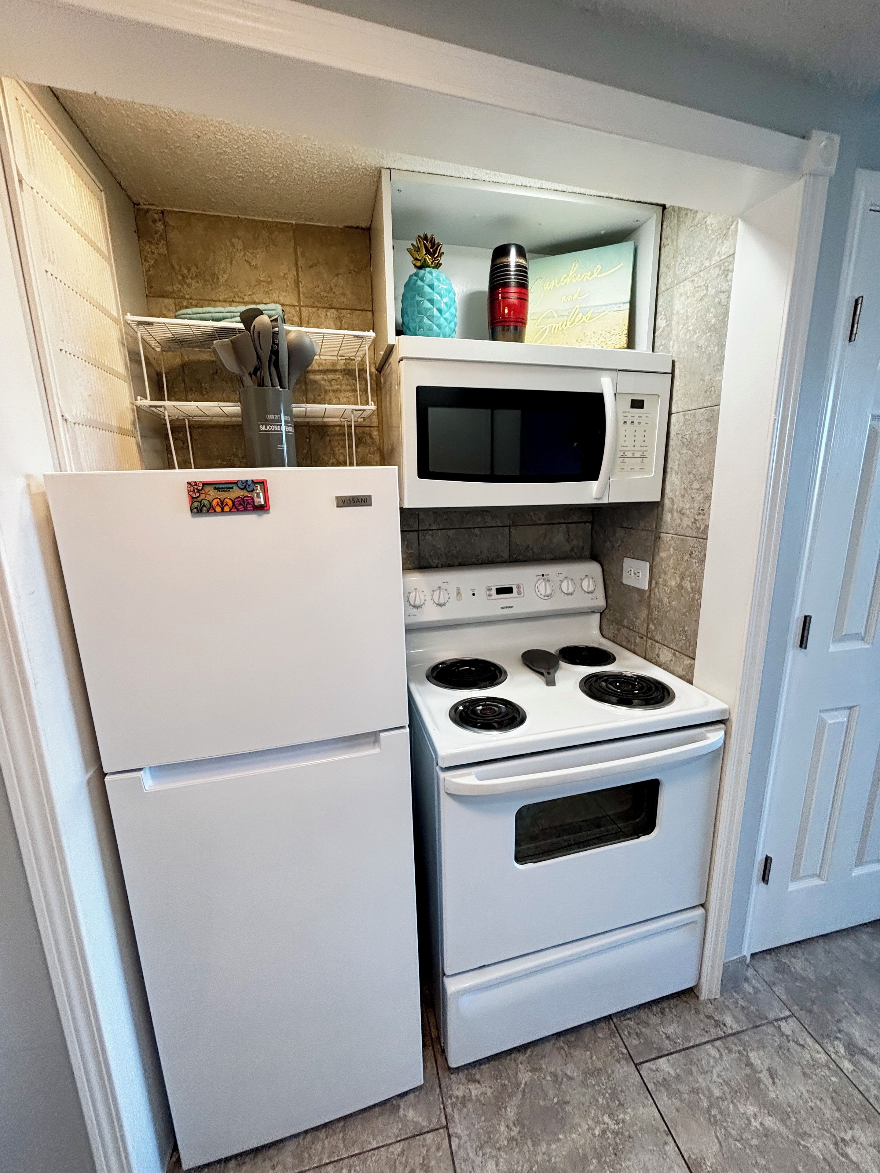 A compact kitchen with a white refrigerator, a microwave, and a stove.