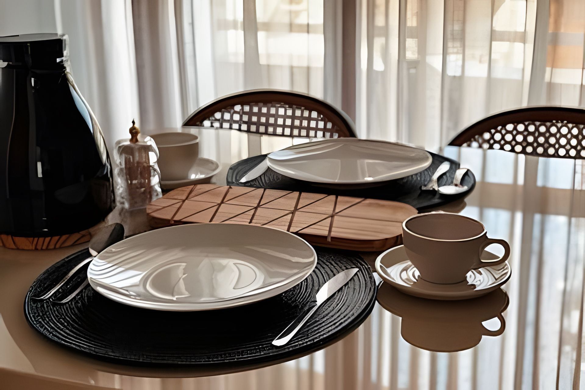 Una mesa de comedor dispuesta con platos, cubiertos, una taza y una cafetera.