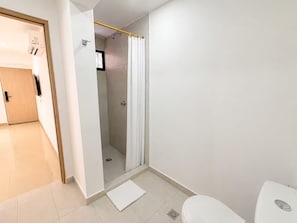 Een badkamer met een douche, toilet en een deur naar een andere kamer.