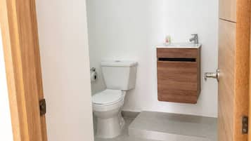 Un bany amb vàter, un armari de fusta i una porta.