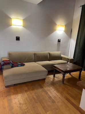 Un soggiorno con un divano modulare beige, un tavolino in legno e due lampade a parete.