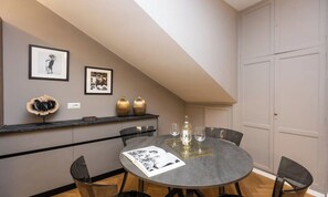 Ein Essbereich mit einem runden Tisch, Stühlen, einem gerahmten Bild und einer Vase an der Wand.