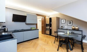 Una cocina moderna con armarios grises, encimera negra y un comedor con una mesa redonda y sillas.