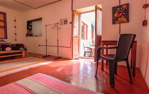 Una habitación con suelo de madera, una silla negra, una mesa de madera, un espejo y una ventana con vistas al exterior.