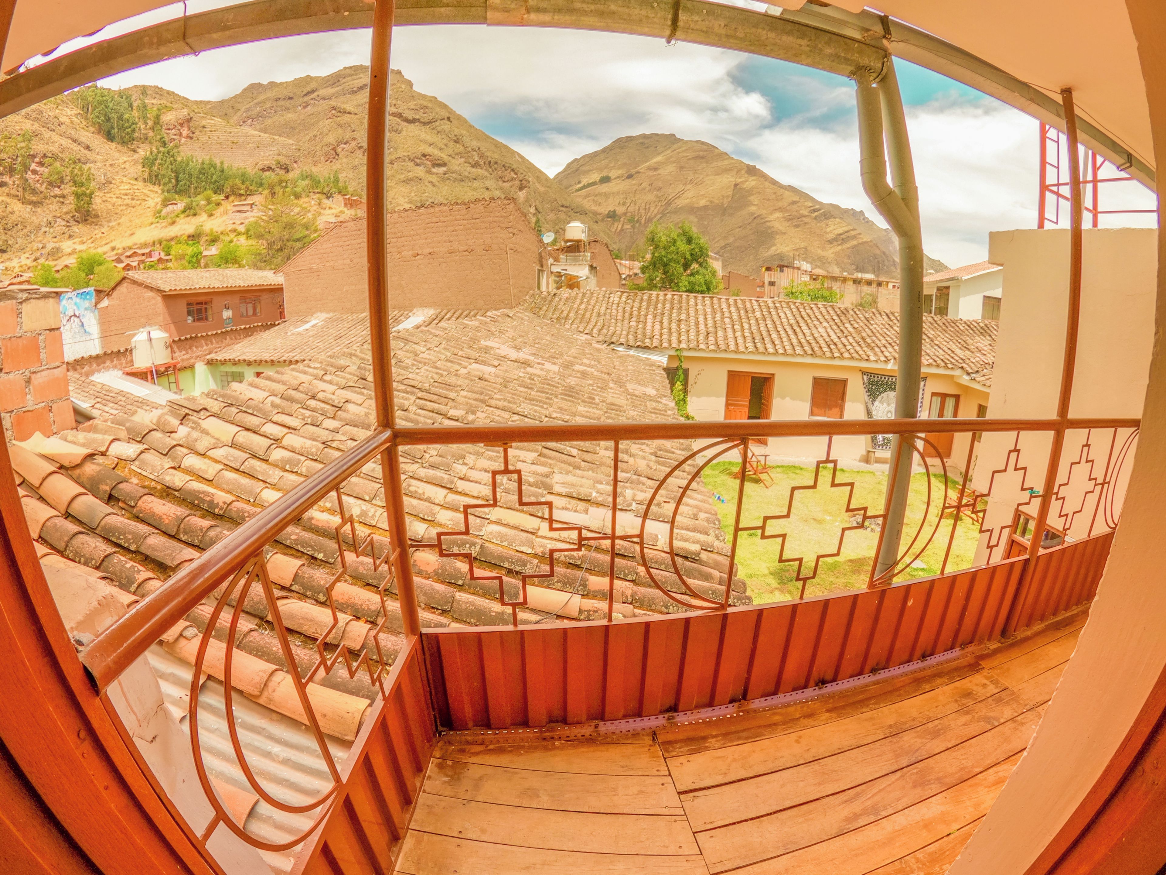 A balcony with a view of a mountainous landscape, terracotta roof tiles, and a metal railing.
