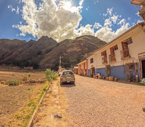 Un camino de grava que conduce a un edificio con el paisaje de una montaña al fondo.