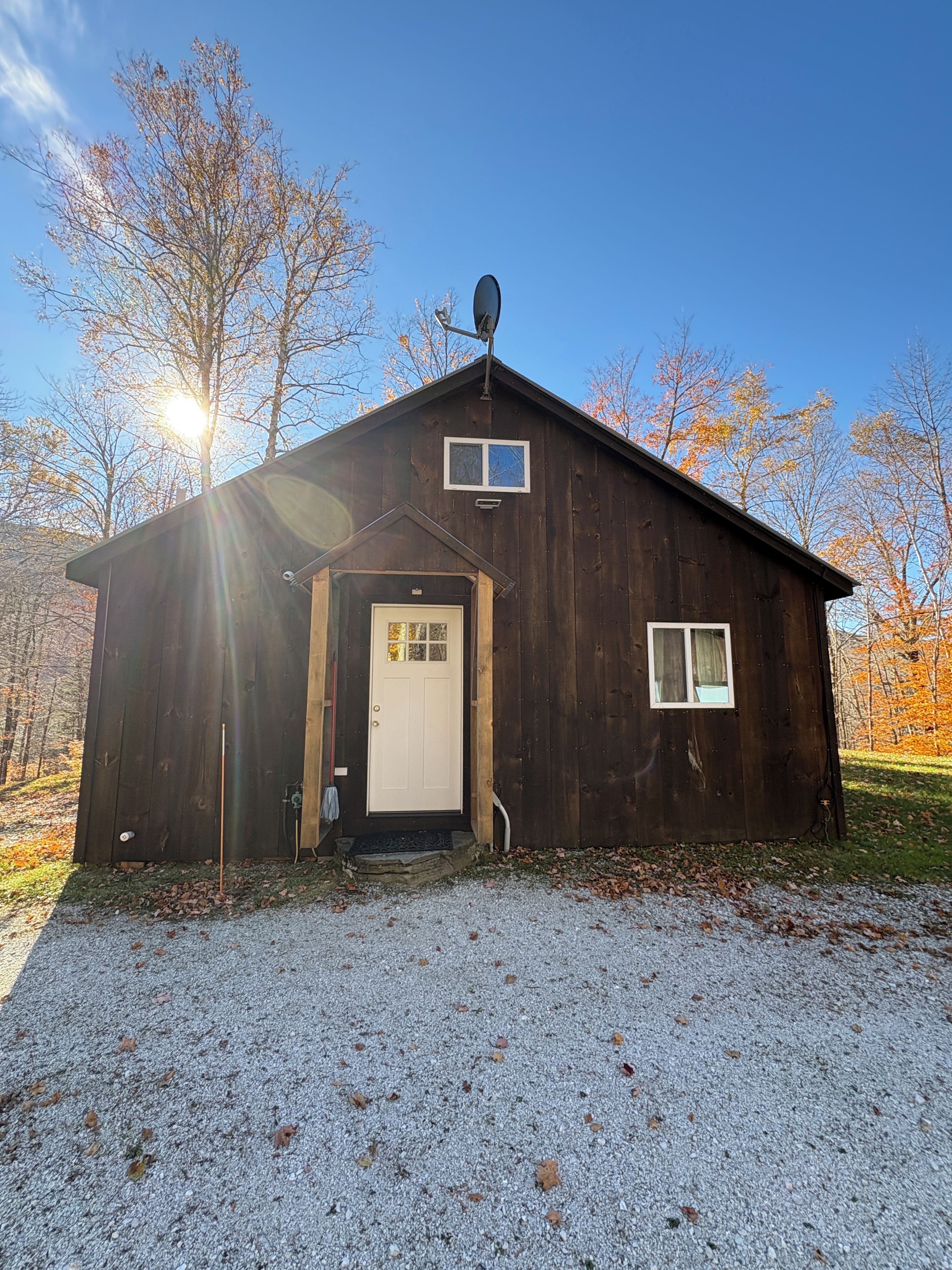 A wooden cabin with a door, a small window, and a satellite dish.