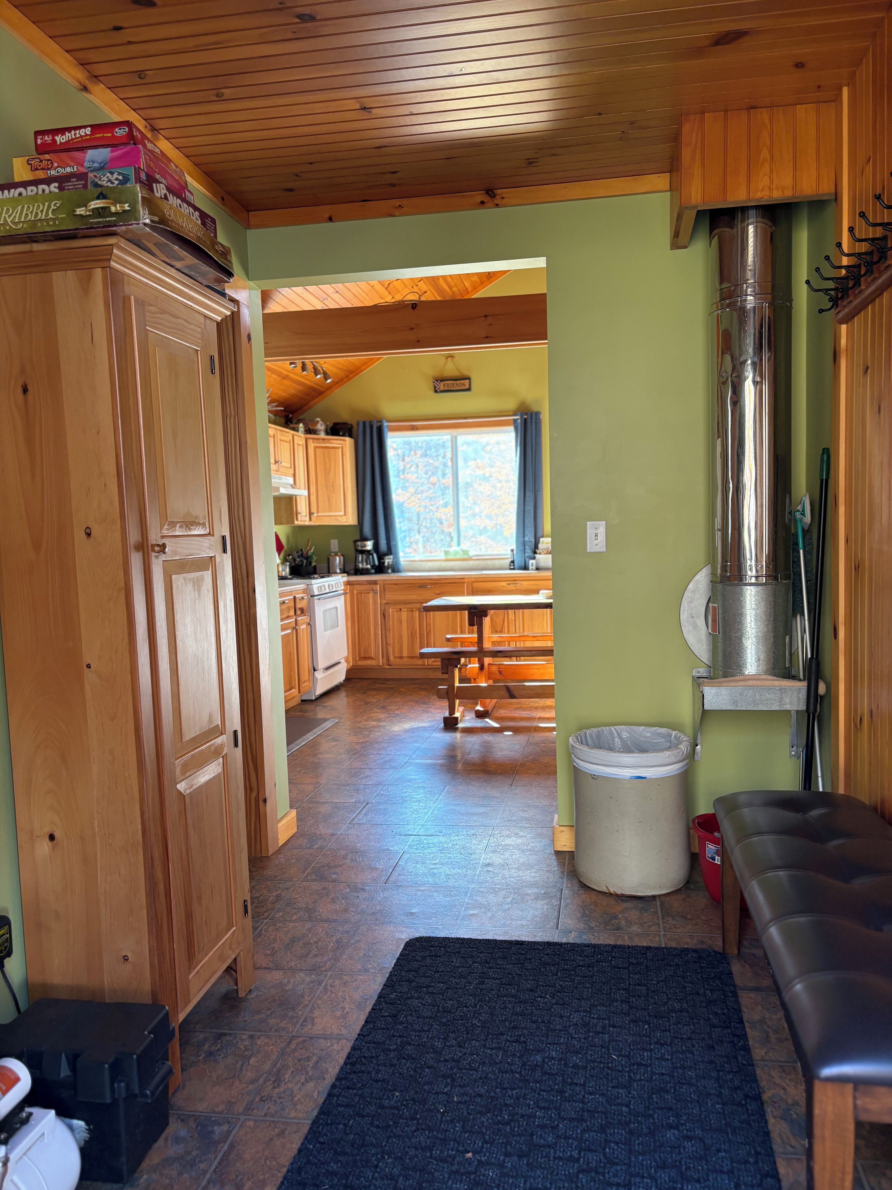 A wooden interior with a kitchen area, a dining table, and a bench.