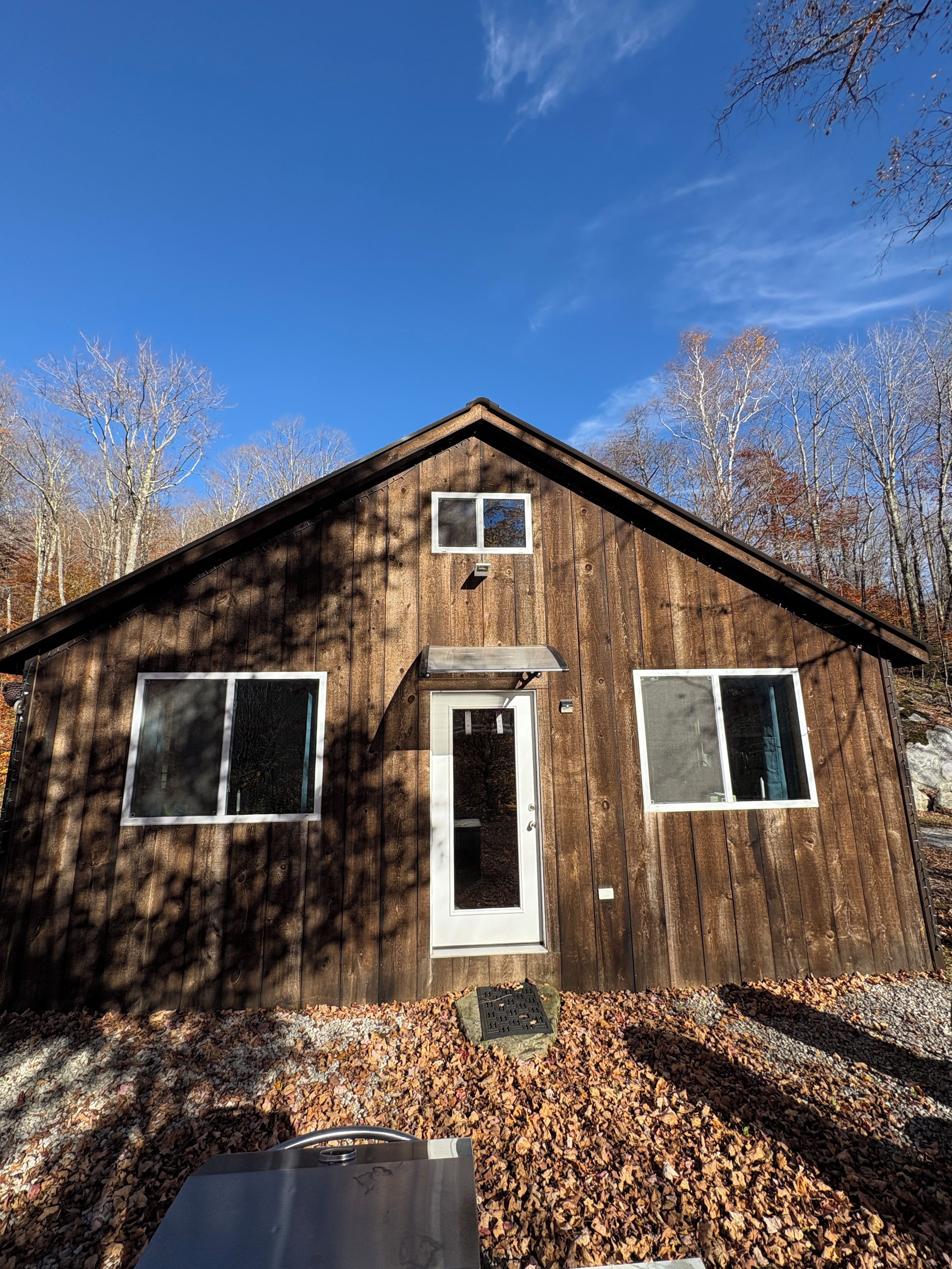 A wooden cabin with a front door, two windows, and a small porch area.