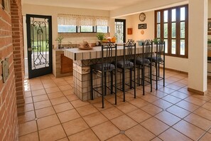 A kitchen with a central island, bar stools, and a dining table.