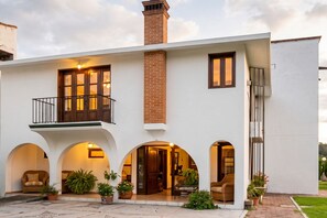 A modern two-story house with a balcony, arched windows, and a brick chimney.