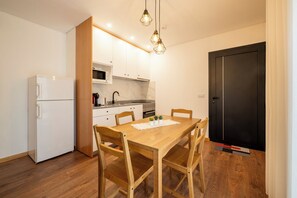 Une cuisine de taille réduite avec des meubles blancs, un four à micro-ondes et une porte noire.