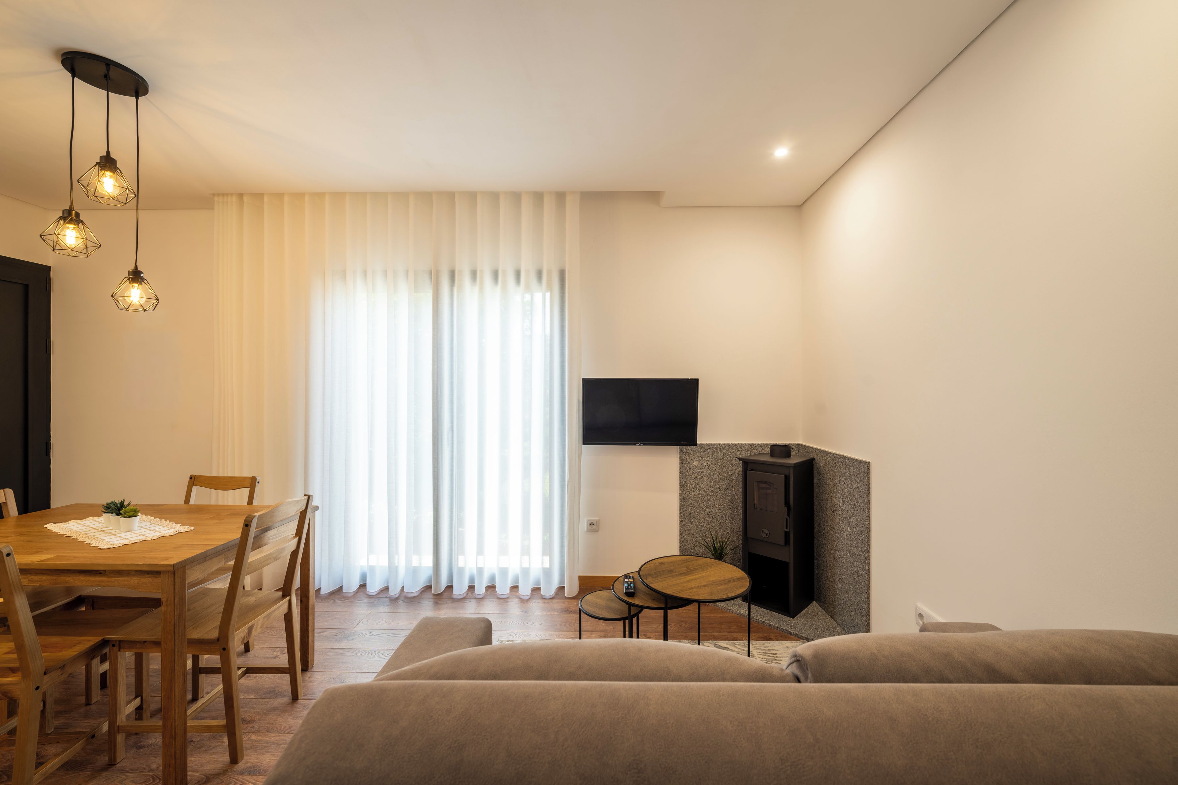 Ein modernes Wohnzimmer mit einem Holzespeisetisch, zwei Sofas, einem an der Wand montierten Fernseher und einem Kamin.