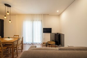 Ein modernes Wohnzimmer mit einem Holzespeisetisch, zwei Sofas, einem an der Wand montierten Fernseher und einem Kamin.