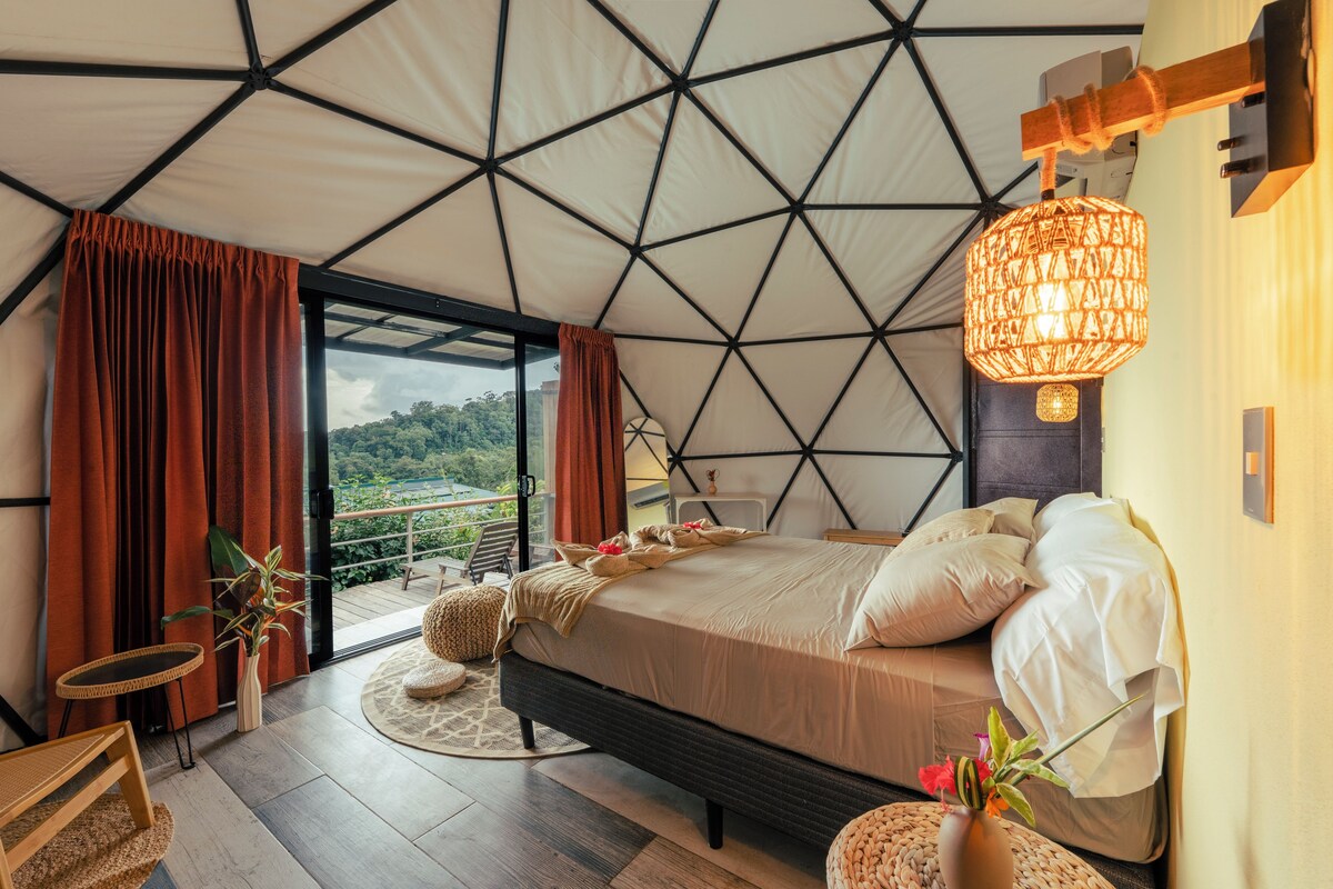 Une chambre dotée d’un grand lit, offrant une vue sur l’extérieur et présentant un plafond au design géométrique original.