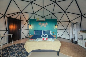 A tent-style room with a bed, wall decorations, and a hanging robe rack. - Sukia Kin Glamping and Retreats (Drake Bay)
