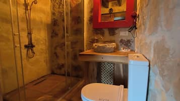 Un baño con cabina de ducha de vidrio, un inodoro blanco y un espejo con marco rojo.
