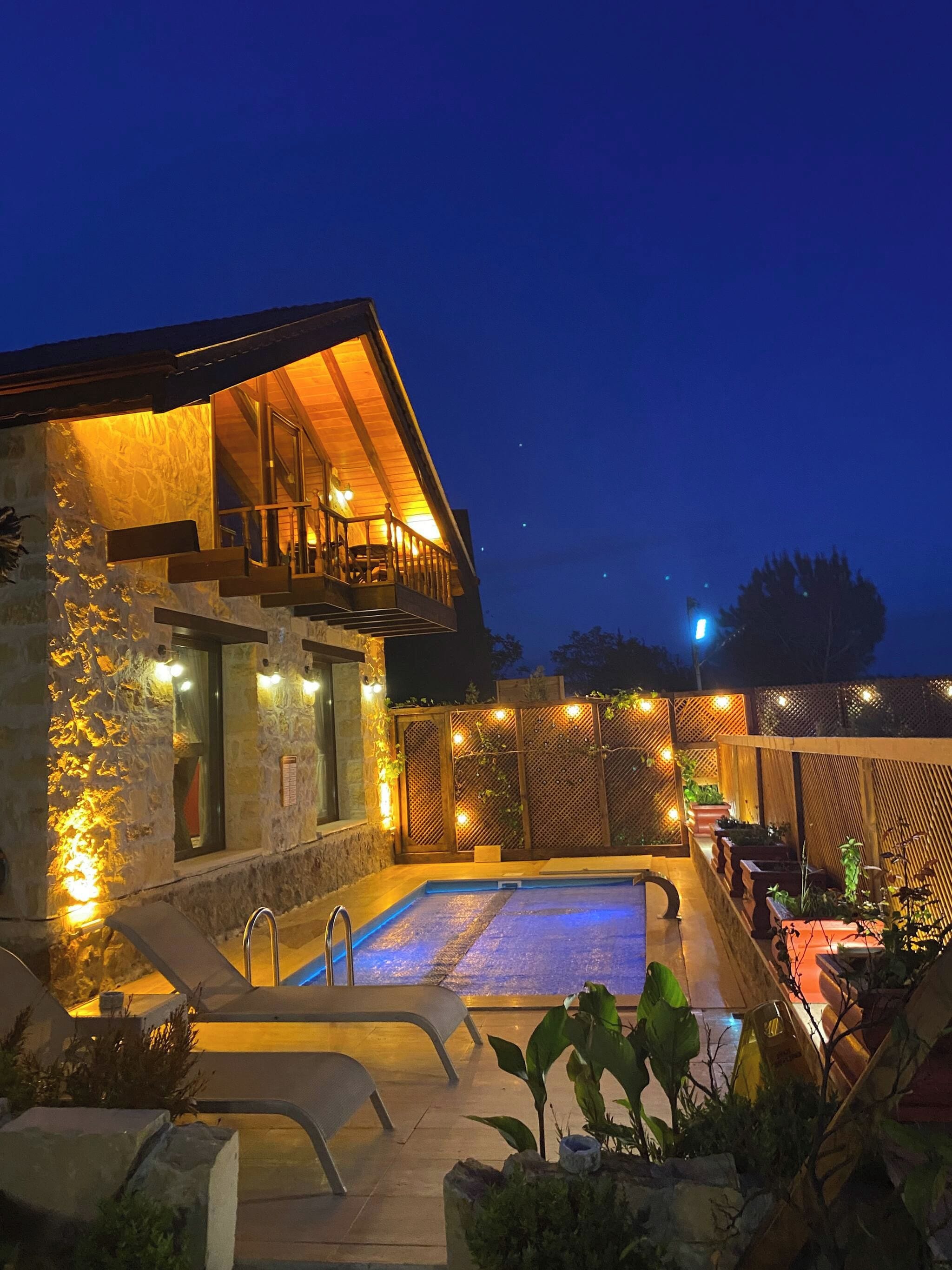 Ein zweistöckiges Gebäude mit Swimmingpool, Sitzgelegenheiten im Freien und Steinmauern.