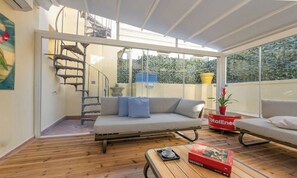 Een moderne woonkamer met houten vloer, een bank, een salontafel en een trap naar een verdieping.