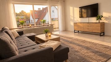 Un salon moderne avec un canapé, une table basse et un téléviseur fixé au mur.