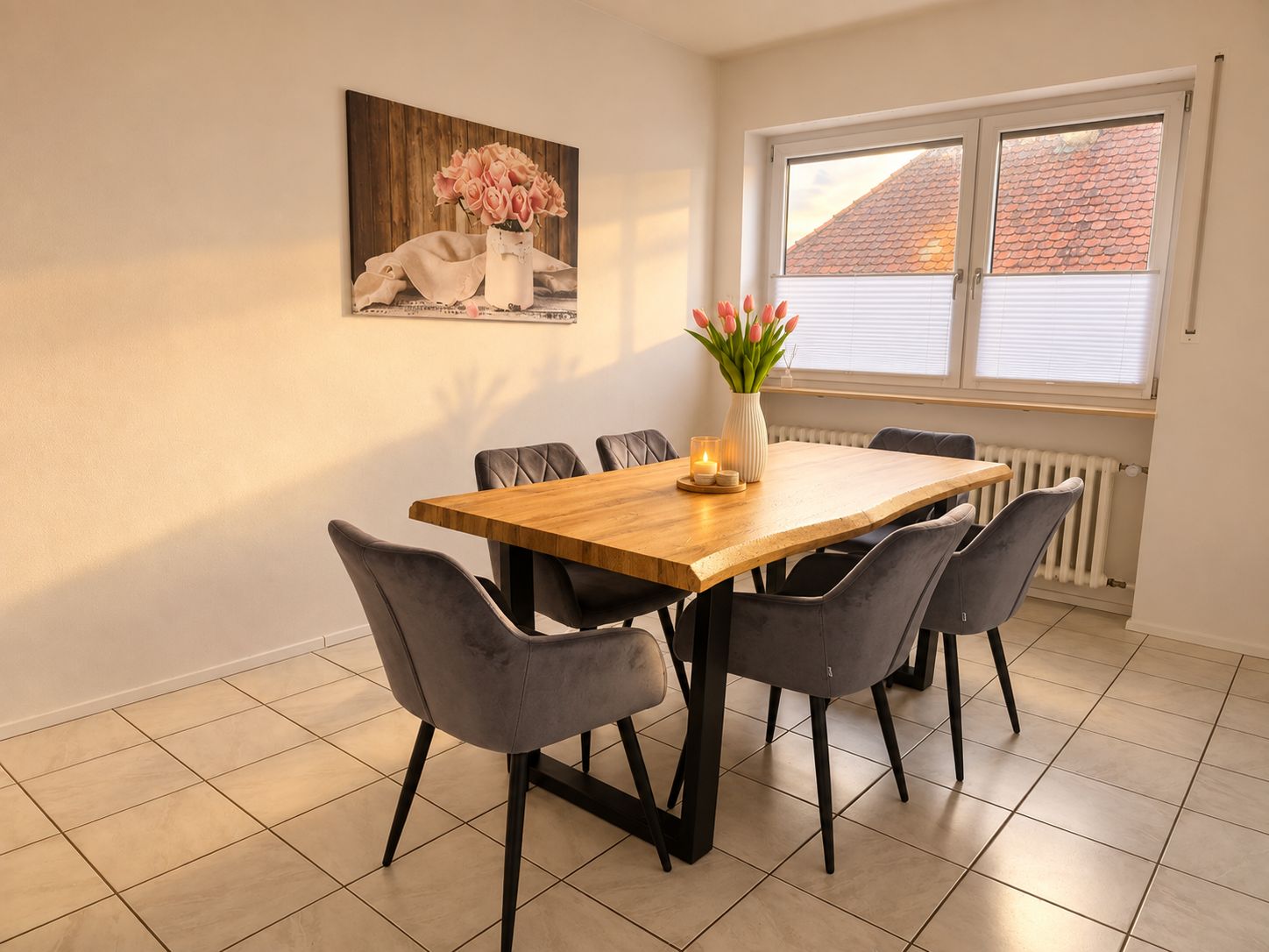 Un coin repas avec une table en bois et six chaises, un vase avec des fleurs et une fenêtre avec des stores.