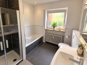 Une salle de bain moderne avec une douche à parois de verre, une baignoire sur pieds, des toilettes et un lavabo avec un miroir.