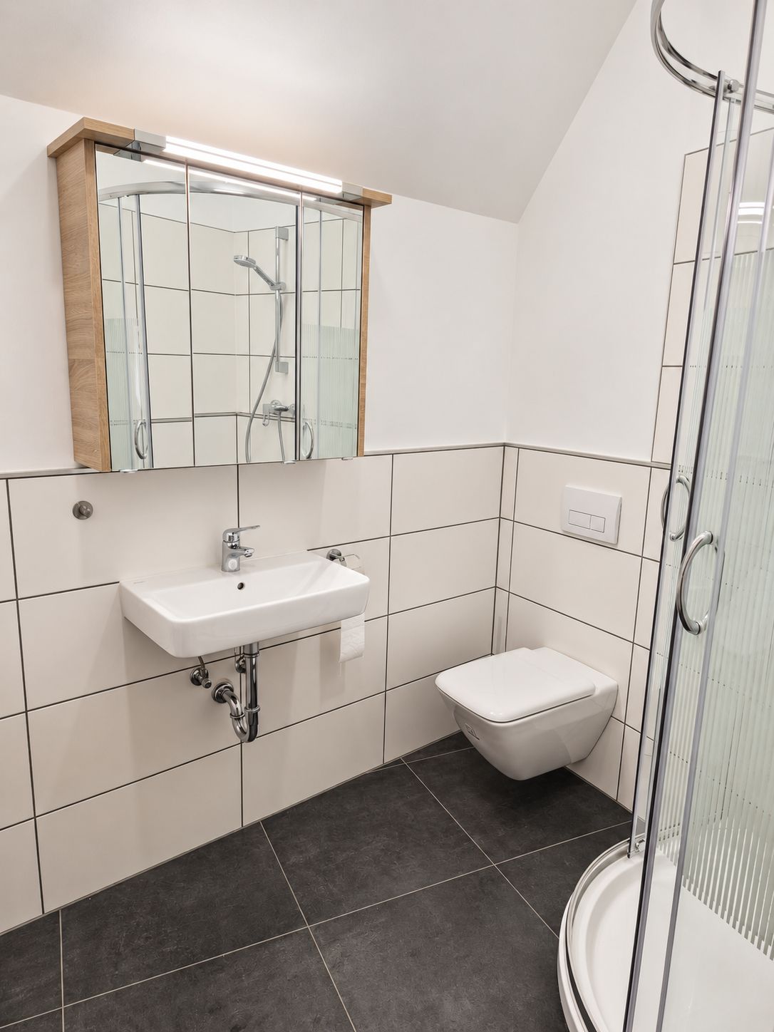 Een moderne badkamer met een wit wastafelmeubel, een toilet en een douchecabine met glazen wanden.