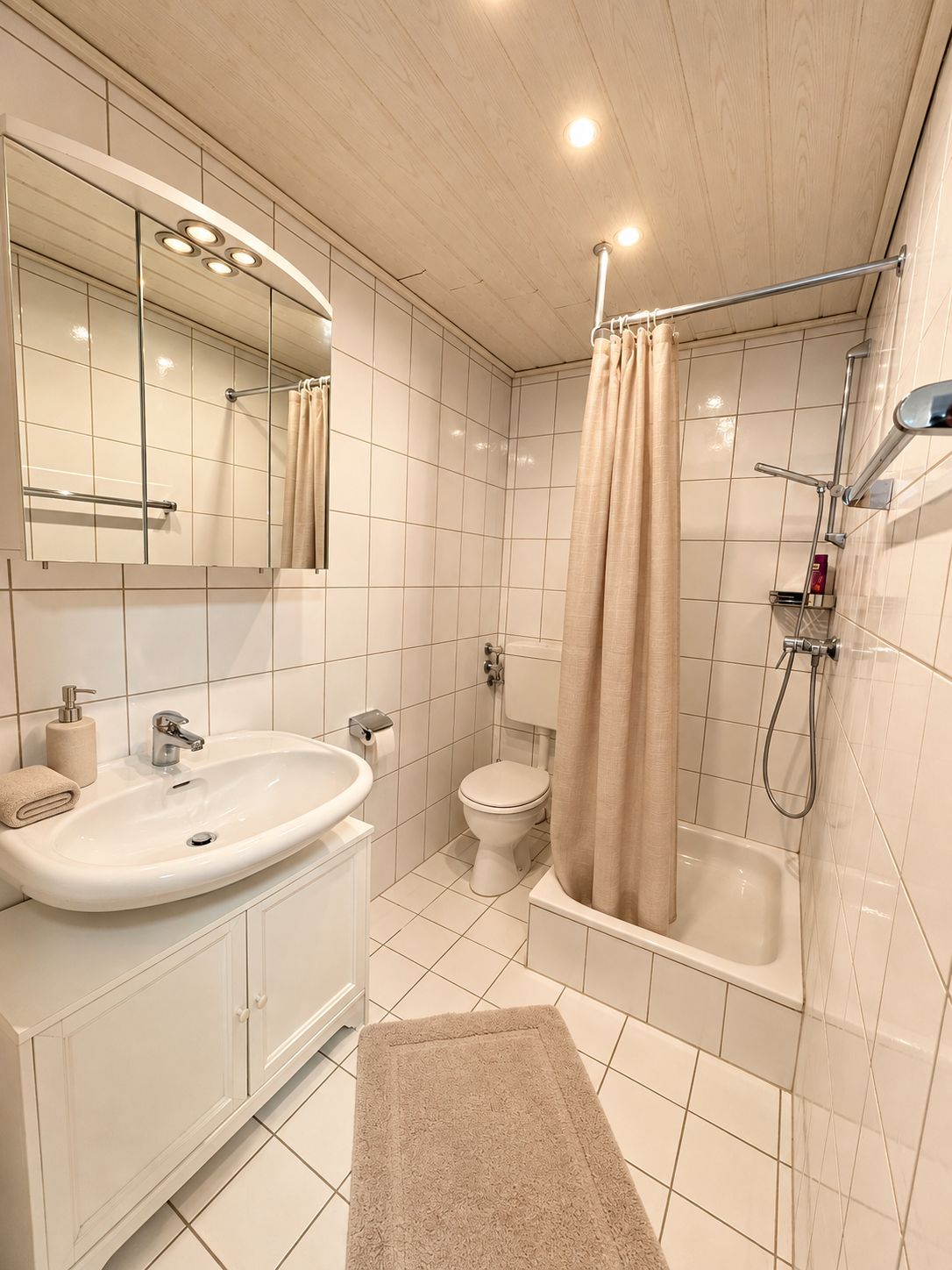 Een badkamer met een wastafel, toilet, douche en spiegel.