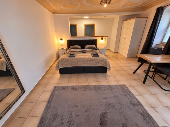 A bedroom with a bed, bedside tables, a mirror, a desk, and a chair. - Modern Apartment in a Historic Estate (Ochsenfurt)