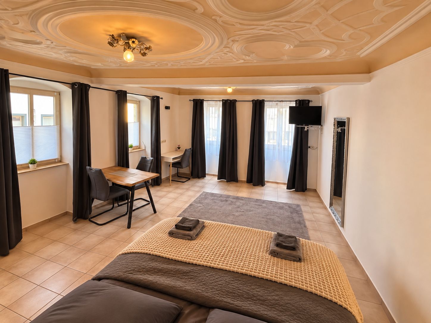 Een hotelkamer met een bed, een bureau, een stoel, een televisie en een raam met gordijnen.