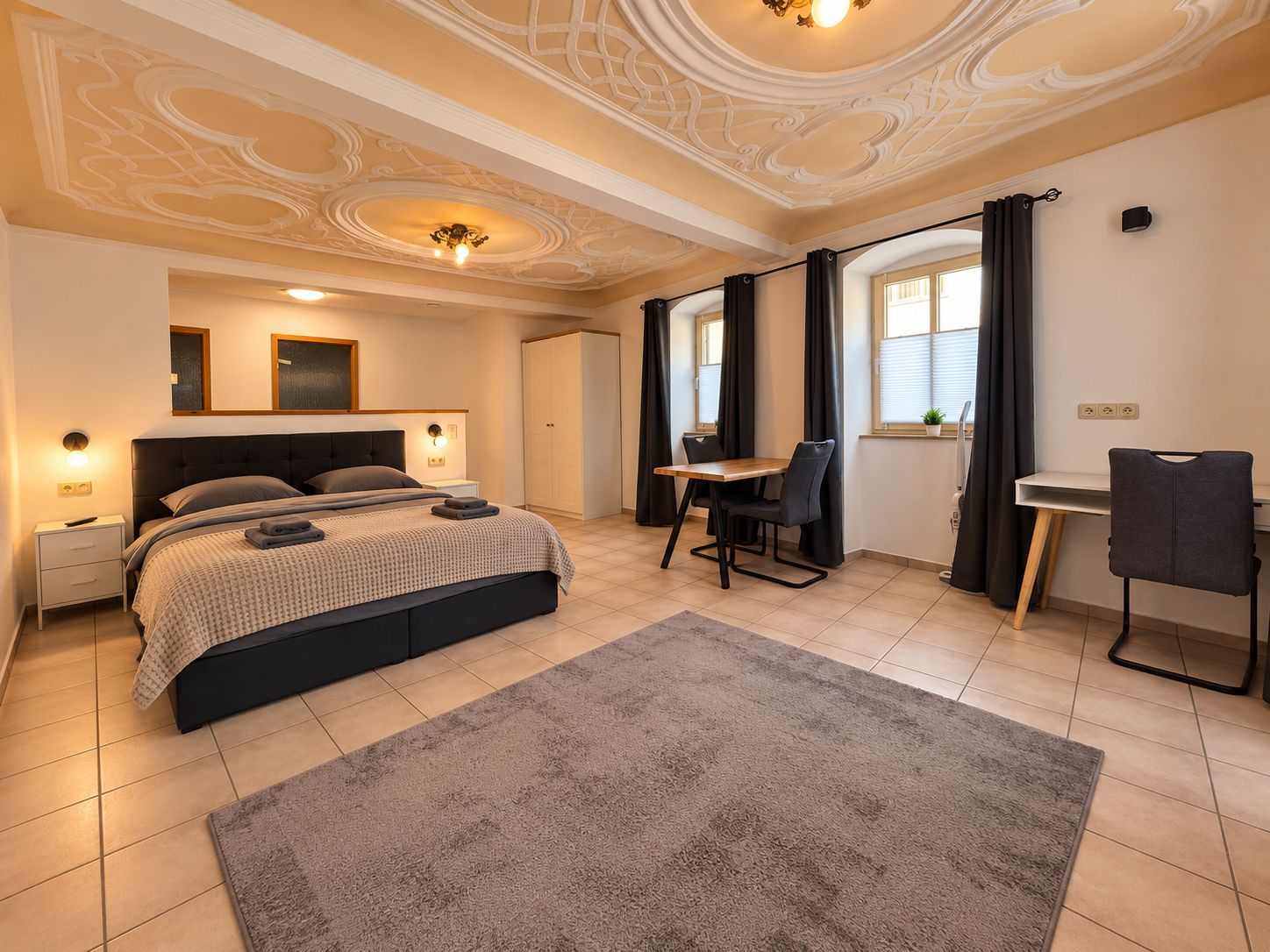 Een slaapkamer met een bed, nachtkastjes, een bureau en een stoel.