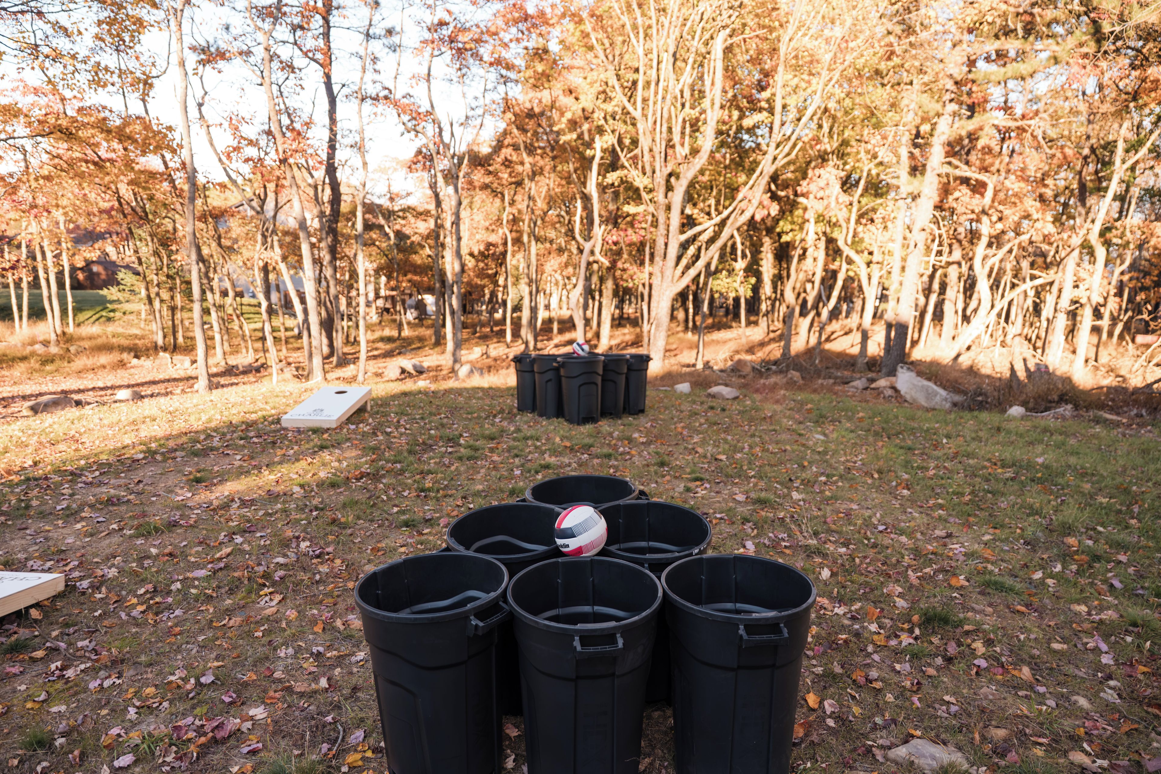 A row of black trash bins in a park with trees in the background.