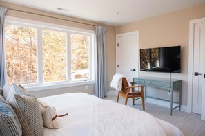 A bedroom with a large bed, a desk, a chair, a television, and a window with curtains. - NEW Luxe 6BR | Speakeasy, Cinema, Hidden Playroom (Albrightsville)