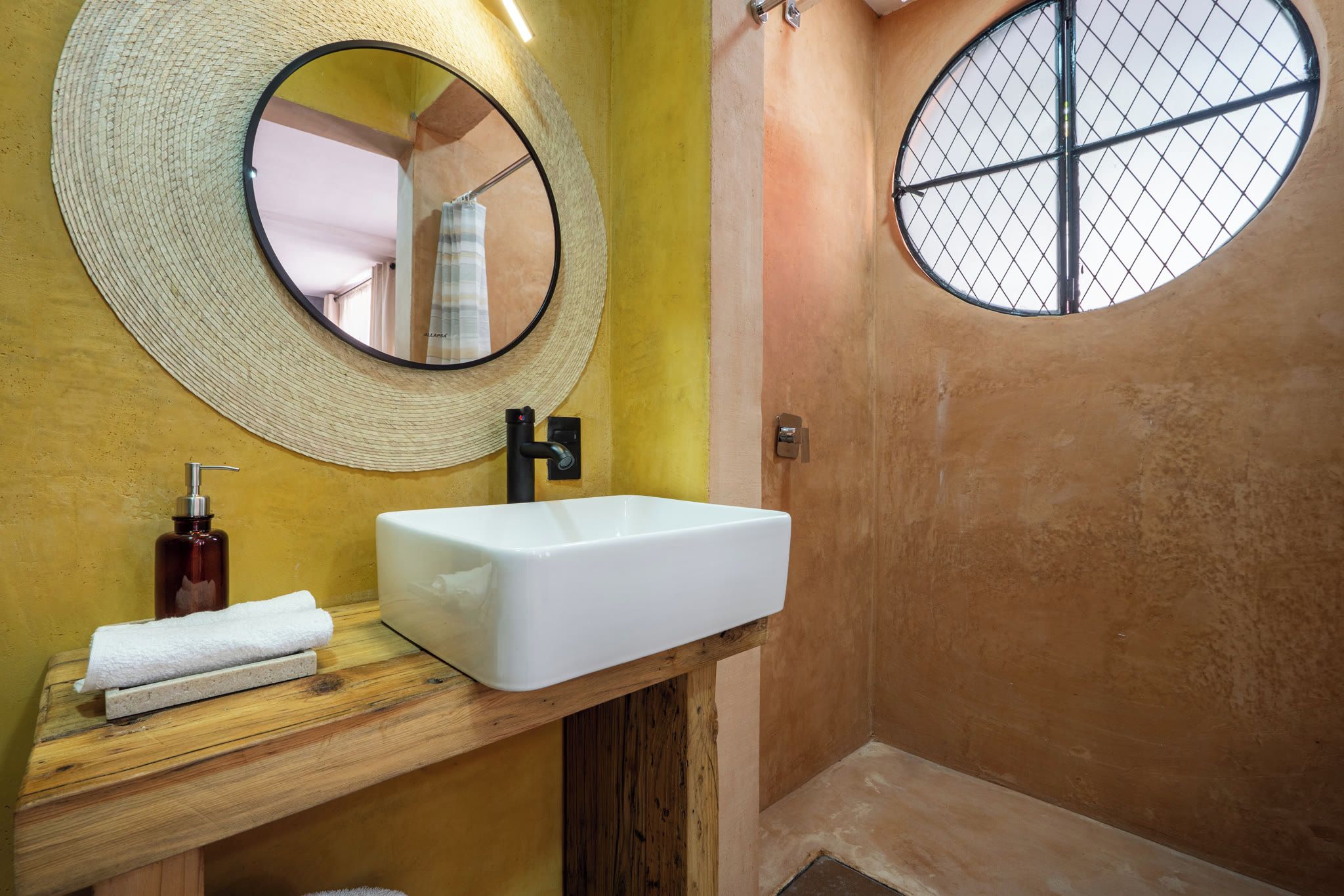 Un baño con un lavabo blanco, un espejo y una toalla en la encimera.