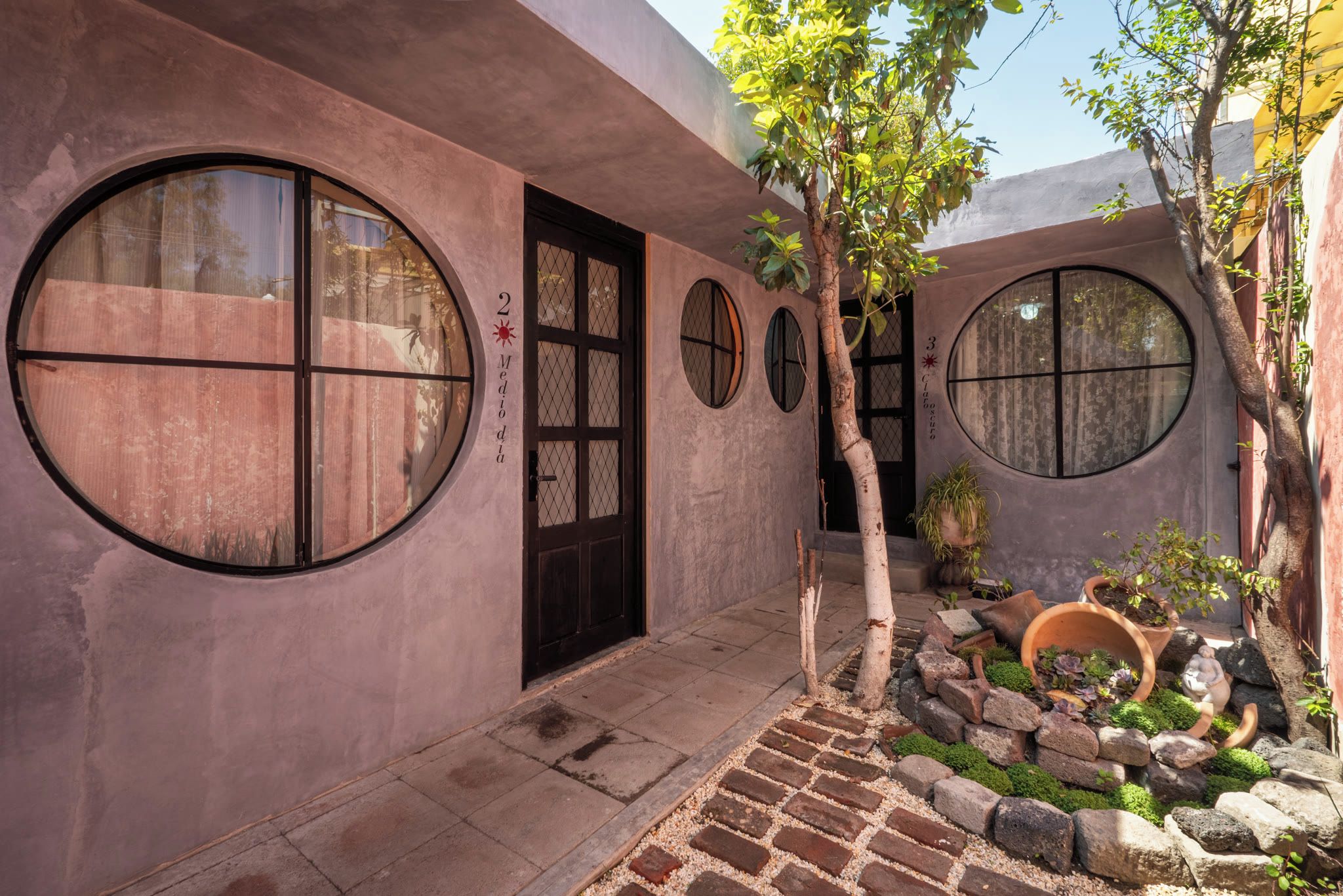 A building with circular windows, a door, and a small garden with rocks and plants.