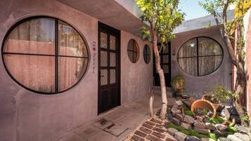 A building with circular windows, a door, and a small garden with rocks and plants.