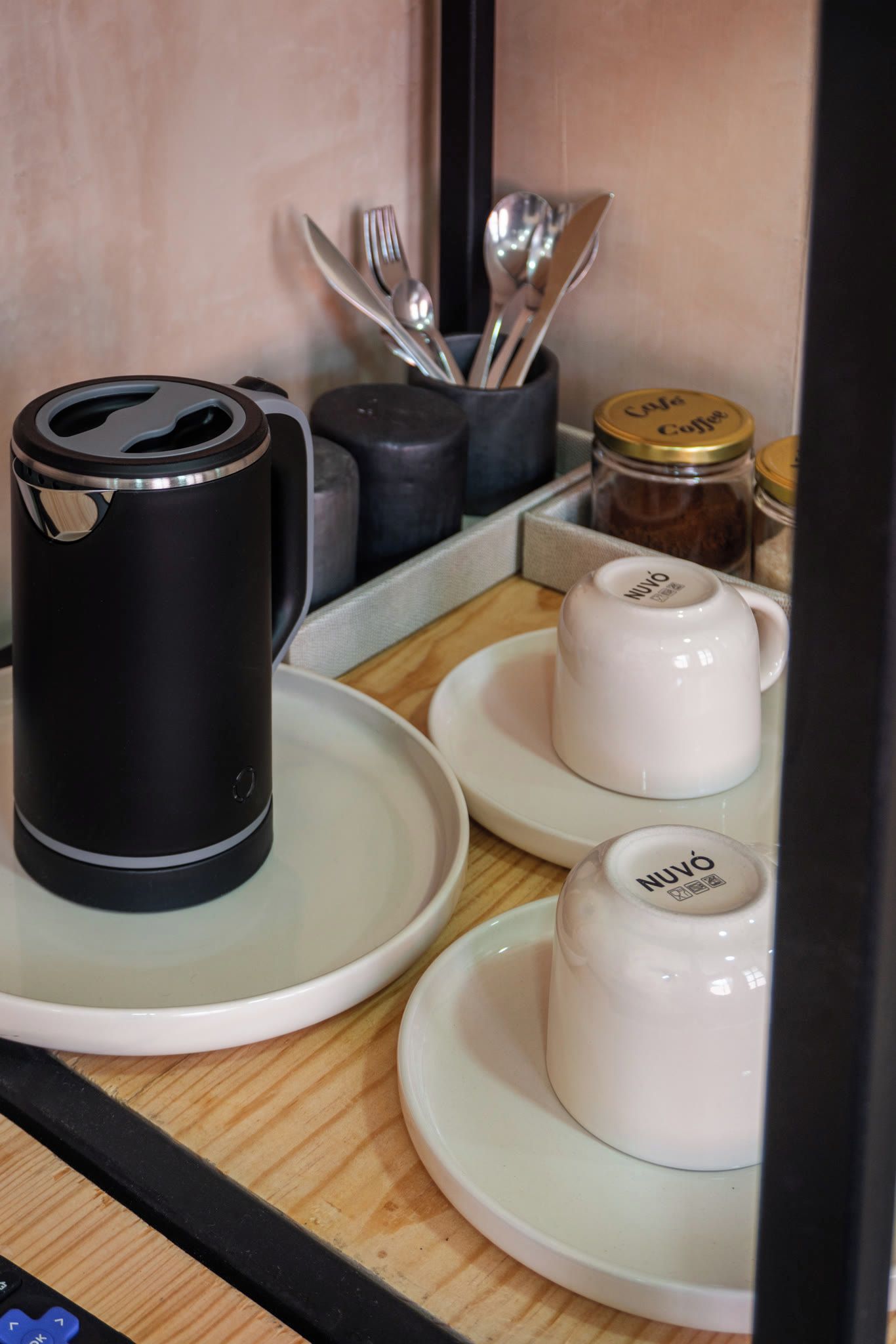Eine Küchenzeile mit Kaffeemaschine, zwei weißen Tassen, einem Kaffeeglas und Besteck.