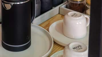 Eine Küchenzeile mit Kaffeemaschine, zwei weißen Tassen, einem Kaffeeglas und Besteck.