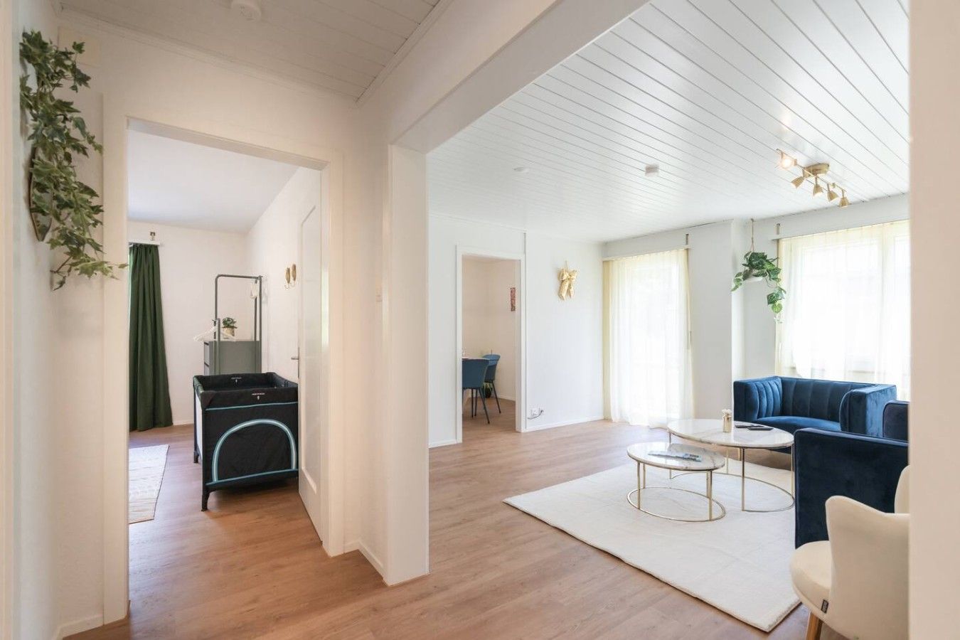 Ein modernes Wohnzimmer mit einem blauen Sofa, einem Couchtisch und einem Essbereich mit Tisch und Stühlen.